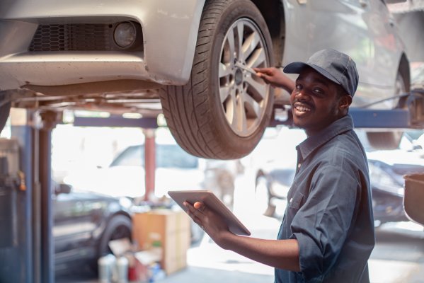 Mechanic fixing a car while checking warranty